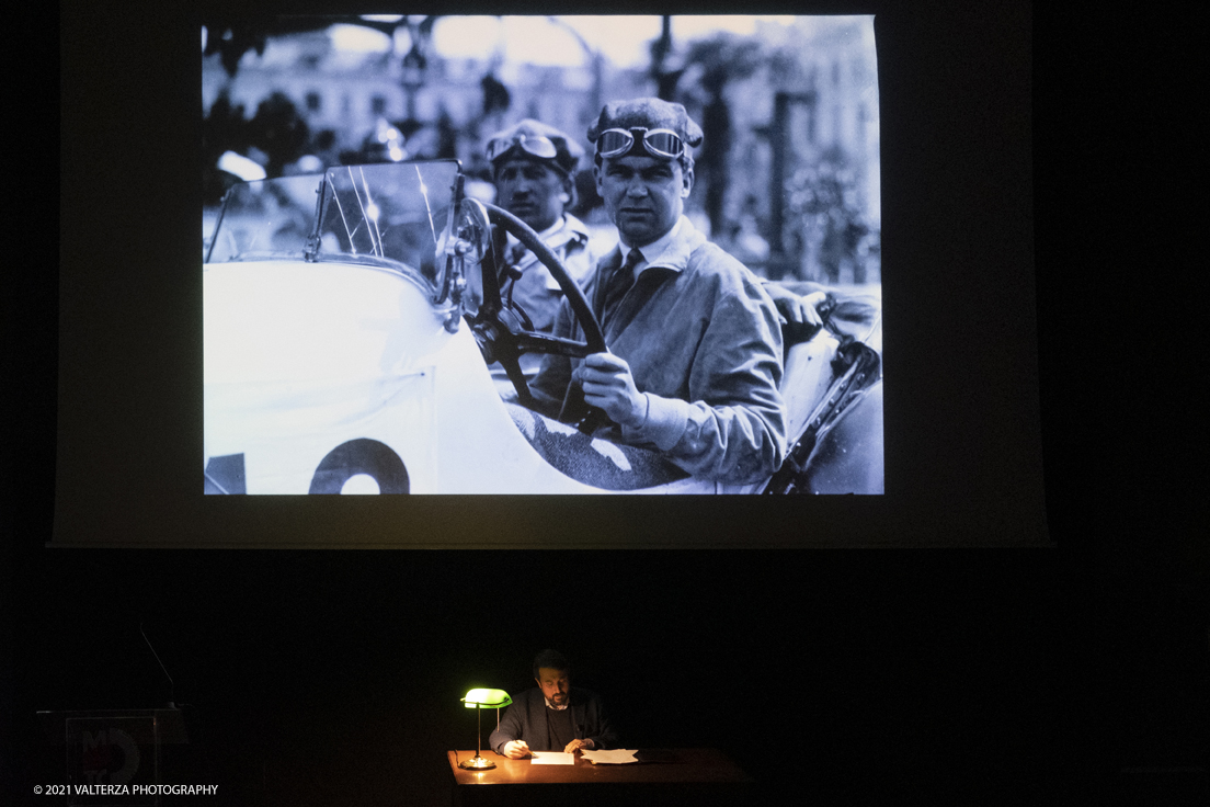 _DSF5763.jpg - 26/10/2021. Torino. Una mostra fotografica con le immagini del fotografo Adriano Scoffone racconta gli anni â€˜20 e â€˜30 della Provincia Granda e gli audaci piloti della Cuneo - Colle della Maddalena Nuvolari, Varzi, Campari e diversi altri. Nella foto mentre vengono proiettate alcune delle 80 immagini costituentti la mostra l'attore Paolo Giangrasso legge una immaginaria lettera scritta da Varzi alla mogglie carolina