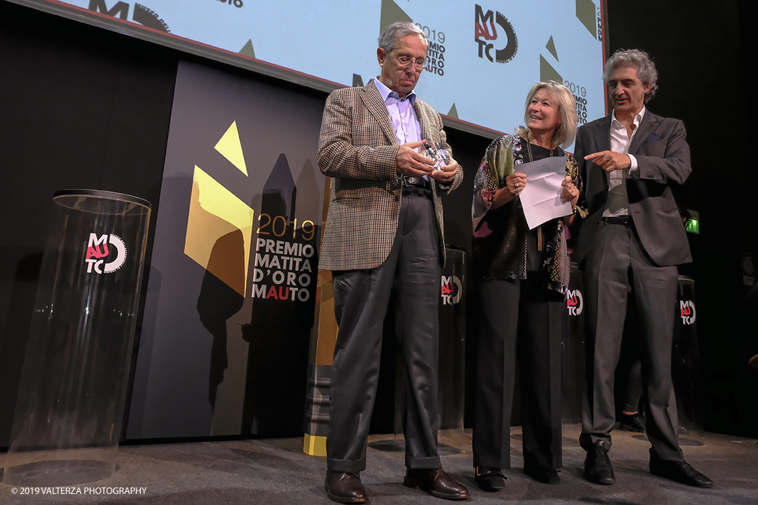 _DSF1547.jpg - 15/10/2019. Torino. Matita d'oro 2019. Anche quest'anno il Mauto ha assegnato i suoi prestigiosi premi al mondo dell'automobile. Nella foto Il premio MAUTO â€œCarlo Biscaretti di Ruffiaâ€� va allâ€™ Ing Mauro Forghieri  lâ€™insuperabile creativitÃ  ingegneristica e gli straordinari successi ottenuti su strada e su pista: durante gli anni in cui Ã¨ stato Direttore Tecnico della Scuderia Ferrari. Consegnano il premio  Mariella Mengozzi e Benedetto Camerana.