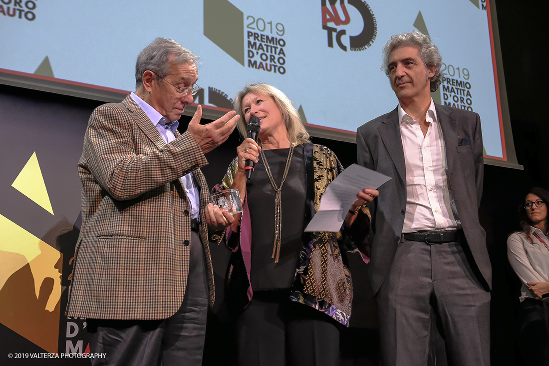 _DSF1559.jpg - 15/10/2019. Torino. Matita d'oro 2019. Anche quest'anno il Mauto ha assegnato i suoi prestigiosi premi al mondo dell'automobile. Nella foto Il premio MAUTO â€œCarlo Biscaretti di Ruffiaâ€� va allâ€™ Ing Mauro Forghieri  lâ€™insuperabile creativitÃ  ingegneristica e gli straordinari successi ottenuti su strada e su pista: durante gli anni in cui Ã¨ stato Direttore Tecnico della Scuderia Ferrari. Consegnano il premio  Mariella Mengozzi e Benedetto Camerana.