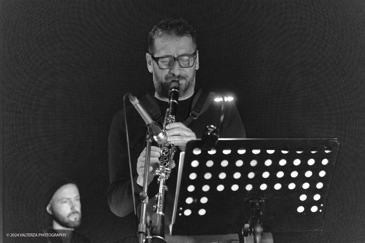 _G3I3710-2.jpg - 27/04/2024. Torino. Francesco Bearzatti, sassofoni, clarinettoStefano Risso, contrabbasso, elettronicaMattia Barbieri, batteriaSimone Sims Longo, elaborazione video . Down Bit Duke offre una rilettura distopica della colonna sonora di Duke Ellington del film di Preminger Anatomy of a Murder (1959). Il beat che Ellington cercava nella sua musica diventa bit nei brani del trio, rappresentando il linguaggio binario del quarto strumento in sala, il computer. Nella foto Francesco Bearzatti e Simone Sims Longo