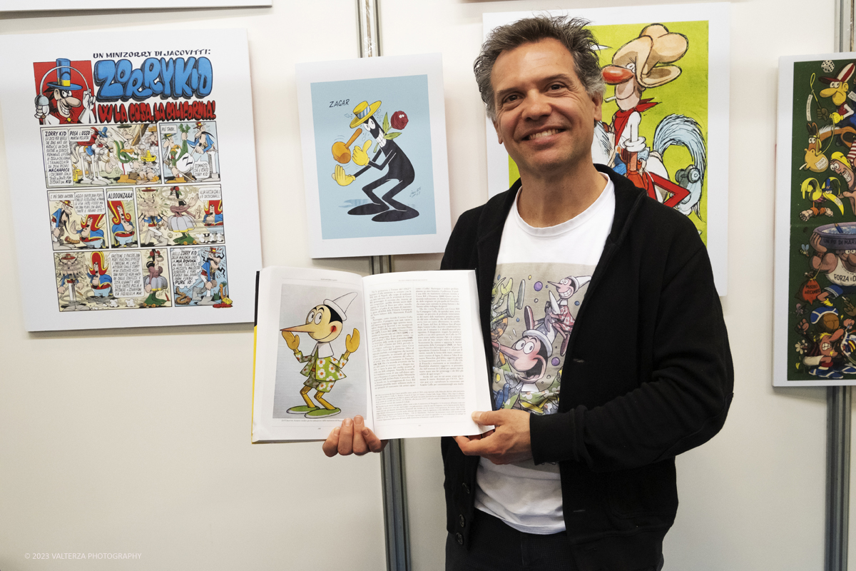 _DSF0399.jpg - 15/04/2023.Torino. Torino Comics celebra i 100 anni dalla nascita di Benito Jacovitti: 1923-2023 , uno degli autori italiani di fumetti piÃ¹ importanti del Novecento. Lâ€™autore Alessandro Santi, Dino Aloi  Marco Di Nicola e salvagno Luca hanno presentato il nuovo libro Tutti i Pinocchi di Jacovitti (Luglio ed.) allo stand di Poste Italiane Ã¨ stata  allestita una mostra dedicata a Jacovitti ed erano disponibili prodotti dedicati allâ€™artista, tra cui una litografia che ritrae il personaggio di Coccobill, un folder e un cofanetto con sei cartoline. Nella foto Alessandro Santi autore del libro Tutti i Pinocchi di Jacovitti