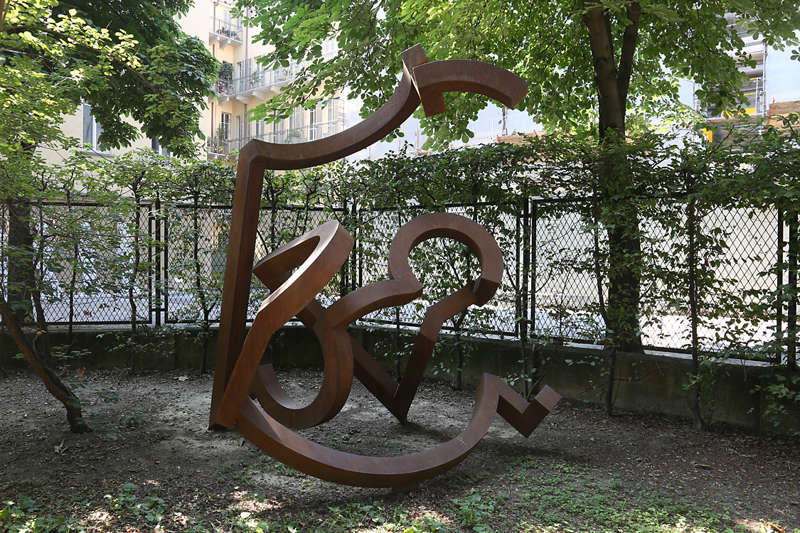 ArteAlleCorti_092.jpg - Riccardo CORDERO - Luogo della memoria - Giardino Palazzo Cisterna L’idea portante di quest’opera è il raggiunto obiettivo di articolare un segno plastico in uno spazio condiviso con lospettatore. Il mito della forma sospesa viene qui giocata con l’articolazione di linee e ritmi decostruttivi e dinamiciper mezzo della persistenza geometrica del cerchio spezzato che si contrappone a linee rette che ne complicanoil percorso visivo. Un riferimento, forse inconscio con l’architettura barocca piemontese.