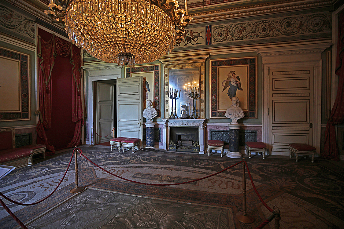 IMG_2913.jpg - Sala dei Dignitari Carlo Alberto, divenuto Re nel 1831, istituì le Reali Villeggiature a Racconigi. Fu quindi necessario adeguare il castello alla nuova funzione destinando alle esigenze protocollari della corte reale il settore Nord della nuova ala Ovest. La Sala dei dignitari, dove i nobili cortigiani sostavano in attesa di udienza dal sovrano, costituisce l'inizio della serie di ambienti con funzione istituzionale: in essi la decorazione, interamente progettata da Pelagio Palagi, vuole esaltare la figura del sovrano attraverso un contesto di immagini e di decorazioni ispirate alla Roma antica e a temi iconografici classici.