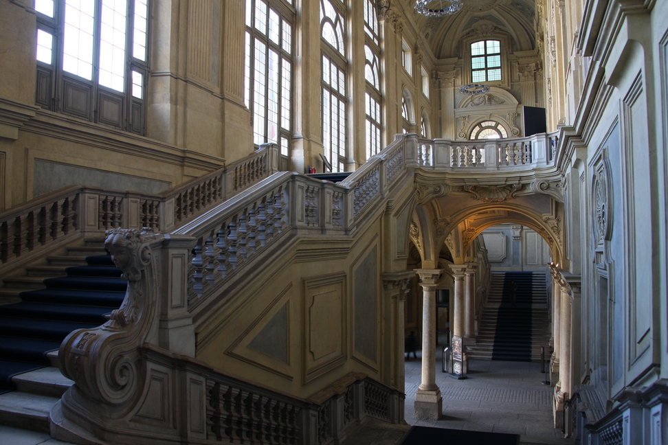 Nuvole_001.JPG - Torino - Palazzo Madama - Scalone progettato da Filippo Juvarra - Palazzo Madama racchiude duemila anni di storia del Piemonte: eretto dai romani con funzione di porta cittadina, Porta Decumana, verso il fiume Po, l'edificio divenne castello difensivo medioevale, e poi palazzo, simbolo del potere che aveva Torino fino al XVI secolo, quando venne preferito l'attuale Palazzo Reale come sede dei duca di Savoia.Abbellito notevolmente sotto la reggenza, nel secolo successivo, dalle due Madame Reali (da qui il nome), il vecchio castello medioevale venne riqualificato grazie all'opera del primo architetto di Casa Savoia, Filippo Juvarra: sua è la grande facciata, che domina la piazza.