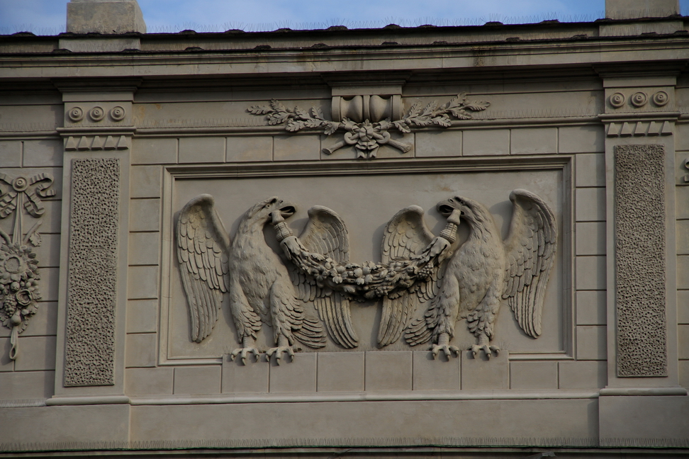 Nuvole_428.JPG - Torino - Piazza Carlo Alberto - Biblioteca Nazionale - Le sue origini risalgono al 1720, quando Vittorio Amedeo II di Savoia diede vita alla Regia Biblioteca Universitaria, frutto dell'unione della raccolta libraria dell'ateneo torinese e del fondo ducale sabaudo. Tra i secoli XVIII e XIX, nell'ottica di sostegno all'attività scientifica promosso dai Savoia, alla biblioteca confluirono molti lasciti e acquisizioni, tra cui, nel 1824, quello dei manoscritti dello Scriptorium dell'abbazia di San Colombano a Bobbio.Dichiarata biblioteca nazionale nel 1873, alla fine dell'Ottocento accoglieva 250.000 volumi, 4.200 manoscritti e 1.000 incunaboli. Il 26 gennaio 1904 un incendio distrusse metà dei manoscritti - alcuni di estrema rarità e valore - e 30 mila volumi. Gli effetti dei bombardamenti del 1942 danneggiarono ulteriormente parte dei volumi a stampa custoditi nella biblioteca. - Aquile con ali spiegate sorreggono fascio di fiori.