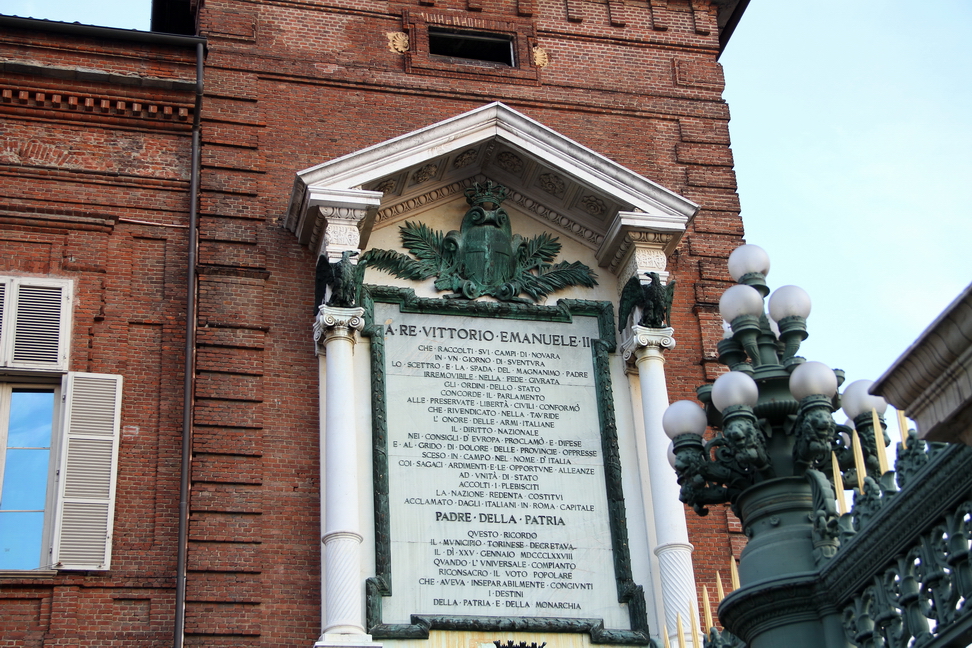 Nuvole_432.JPG - Torino - Piazza Castello - La lapide monumentale con grande stemma reale e cupola a tempietto con ai lati due aquile, dedicata a Vittorio Emanuele II di Savoia (1820-1878), primo sovrano del Regno d'Italia e acclamato Padre della Patria, fu posta nel 1884 sulla loggia di Palazzo Reale.