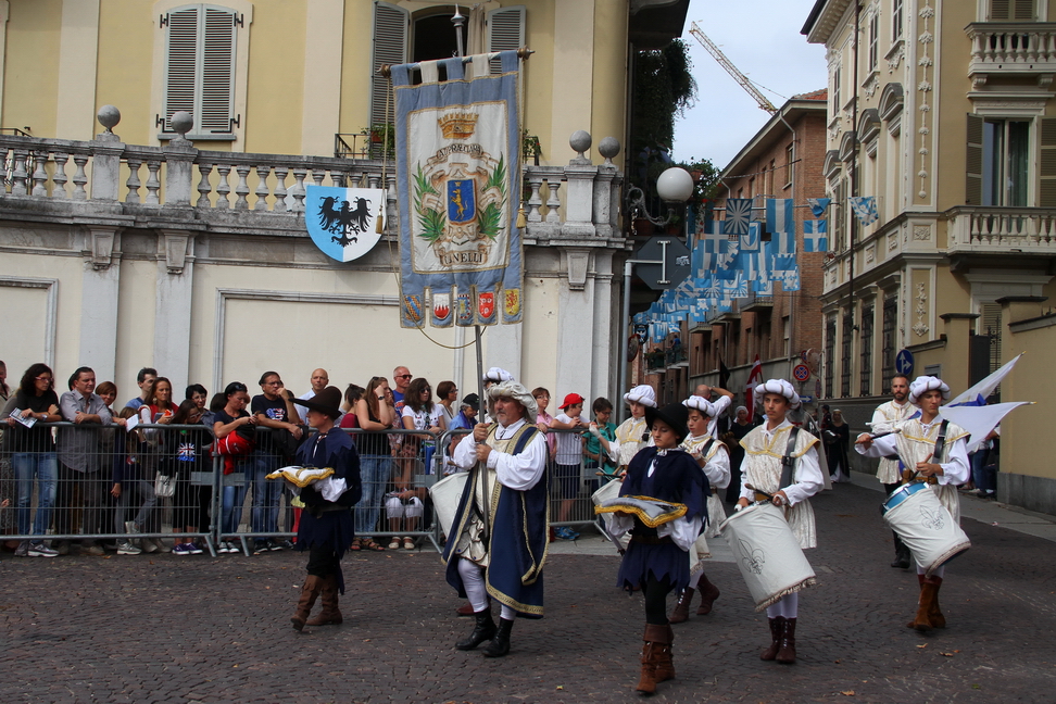 SfilataPalio_106.JPG - CANELLI: I signori di Canelli tra la Corte di Re Manfredi e gli ordini monastico-cavallereschi - Alla metà del XIII secolo numerosi esponenti delle nobili famiglie che costituivano il consortile di Canelli, dopo aver venduto le proprie giurisdizioni feudali al Comune di Asti, emigrarono in Sicilia alla corte di re Manfredi . Imparentati con il giovane sovrano per parte della madre di lui, Bianca Lancia di Agliano, essi si distinsero per fortunate carriere presso la corte sveva che li condussero ai vertici dell’organizzazione del regno. La conquista angioina della Sicilia (1266) significò per i nobili canellesi la perdita delle posizioni guadagnate: furono messi fuorilegge e perseguitati da parte dei nuovi dominatori. Alcuni riuscirono però a trovare rifugio e protezione presso Costanza, figlia di Manfredi, che dal 1262 aveva sposato Pietro III re d’Aragona. Quando gli aragonesi riuscirono a recuperare la Sicilia (1282),  molti membri della famiglia Di Canelli, grazie al favore dei nuovi sovrani, iniziarono fortunate carriere negli ordini  monastico-cavallereschi dei Templari e dei Gerosolimitani, raggiungendo,  tra la fine del Duecento e l’inizio del Trecento, posizioni di primo piano nell’uno e nell’altro ordine Va ricordato fra’ Guglielmo Di Canelli che, Precettore dei Templari in Lombardia, era riuscito  a sfuggire alle persecuzioni angioine. Nel 1290 la regina Costanza si interessò personalmente per fargli ottenere la Precettoria di Sicilia, trovando però opposizione da parte del Gran Maestro dei Templari Guillaume de Beaujeu. Caduto costui durante l’assedio di San Giovanni d’Acri, il suo successore, il celebre Jacques De Molay, diede nuovo impulso alla carriera di fra’ Guglielmo su richiesta di re Giacomo II d’Aragona. Nel 1294 lo stesso sovrano scriveva al Gran Maestro chiedendogli il permesso di trattenere alla sua corte fra’ Guglielmo Di Canelli “…qui nobis consanguinitatis linea est coniunctus” (che è unito a noi per linea di consanguineità). I rapporti di parentela con Bianca Lancia, che avevano fatto ottenere ai Di Canelli il favore di re Manfredi, continuavano a garantire loro la benevolenza dei nipoti, i re d’Aragona.