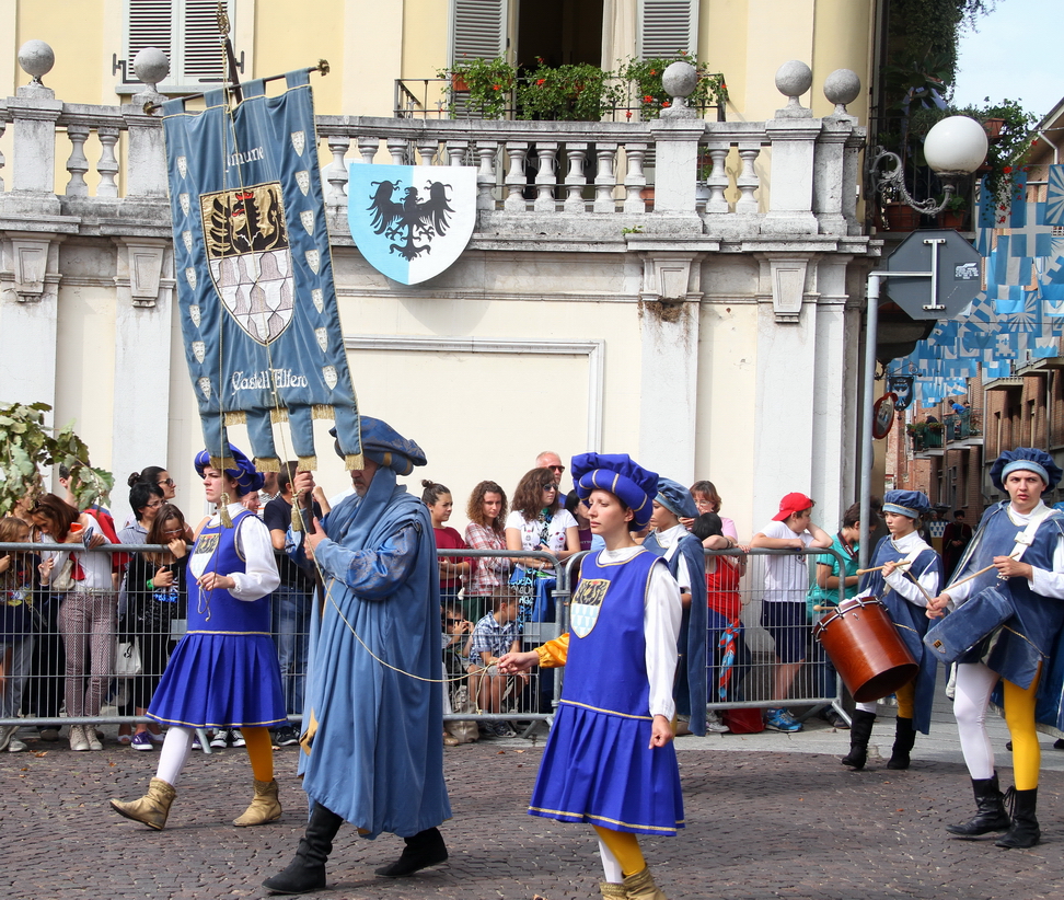 SfilataPalio_183.JPG - CASTELL'ALFERO - “Ad marchum vel libram astensis”. Pesi e misure a Castell’Alfero nel medioevo - Il Comune di Asti imponeva a tutte le terre e villaggi costituenti la "Patria Astensis" di uniformarsi alle misure di peso, lunghezza e capacità in uso nella “capitale”. A tal fine, e sotto pena di pesanti sanzioni, ogni comune e villaggio del territorio astigiano era tenuto a dotarsi di appositi campioni, ai quali dovevano scrupolosamente attenersi i rivenditori, gli esercenti, i dettaglianti e in generale tutti coloro che vendevano merci o derrate a misura e a peso. Ogni anno i consoli o rettori  di ciascun villaggio (e Castell'Alfero tra questi) dovevano  portare in Asti i campioni dei pesi e delle misure per farli verificare, approvare e timbrare presso il palazzo del podestà alla presenza degli Ufficiali del Giudice delle Reve; nell'occasione, gli stessi consoli giuravano di controllare scrupolosamente affinché tutte le merci fossero vendute "ad marchum vel libram astensis". Gli Statuta Revarum, in una “reformagione” del 1475, specificano dettagliatamente quali dovevano essere i campioni delle misure da far verificare in Asti: per le misure di capacità lo staro (circa 50 litri), l'emina (circa 23 litri), il quartirone (12 litri), lo scopello (3 litri), la pinta (1,4 litri), il quartino (0,35 litri), il terzo (0,25 litri) e il mezzo quartino (0,17 litri) per i liquidi e gli aridi. L'alna, pari a circa 120 centimetri, ed il raso pari a  70 centimetri per le misure di lunghezza. La libbra (360 grammi), la mezza libbra (180 grammi), il quartirone (90 grammi), l'oncia ( 30 grammi) e la mezza oncia per il peso. Inoltre si dovevano sottoporre a verifica anche un prototipo di stadera  grande e uno di bilancia.