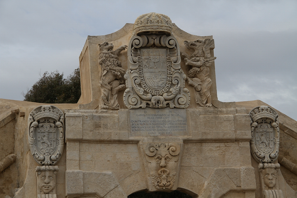 Sicilia_141.JPG - La porta presenta alla sommità due grifoni rampanti, che sorreggono una cornice, sormontata dalla corona di Carlo II di Spagna. Nel riquadro delimitato dal Toson d'Oro è scolpito lo stemma del vicerè D. Francesco Benavides...