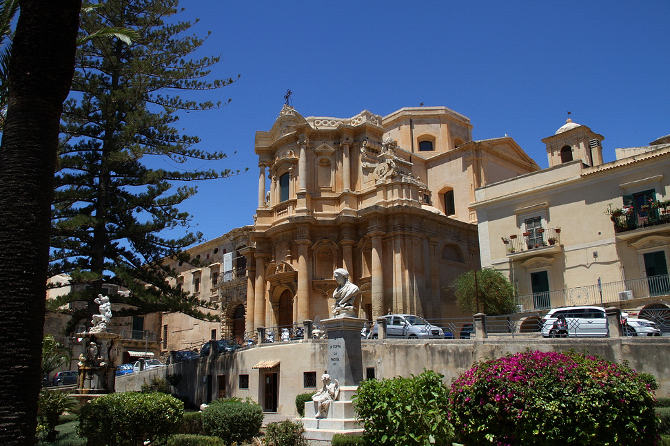 Sicilia_474.JPG - oltre i palmizi e i cespugli si erge la chiesa di S. Domenico, del Gagliardi: è la più colta realizzazione del barocco netino e siciliano; dalla facciata convessa e dalle colonne si sprigionano i riflessi del "barocco dorato", pieni di plasticità ed armonia.